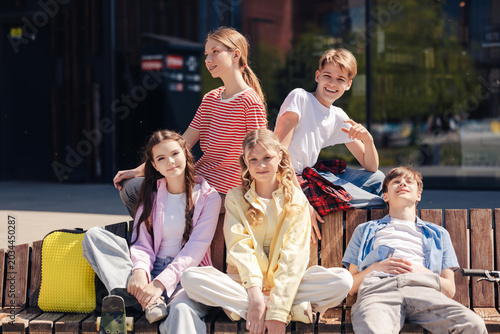 Quadro su tela Diverse group of smiling happy teenagers sitting on the street posing looking at