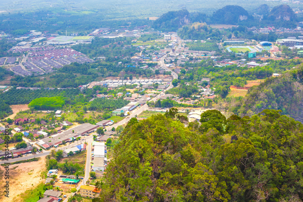 Fototapeta premium High angle view of a town nestled among green limestone mountains in Krabi Thailand. aerial townscape, tropical tourism, scenic viewpoint.