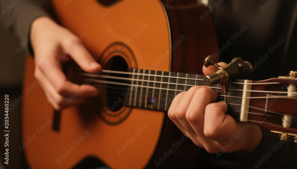 Fototapeta premium Person playing an acoustic guitar in a dimly lit room