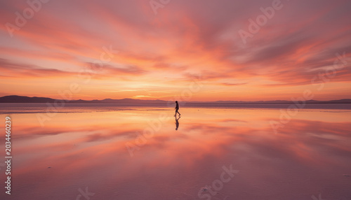 Woman walking along a salt flat at sunset