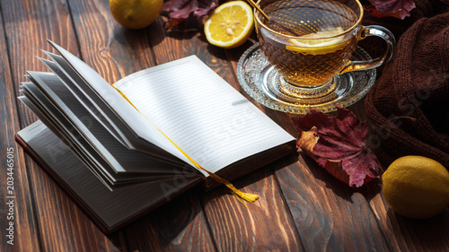 Cozy autumn morning with notebook, tea, and falling leaves
