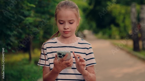 kid smiling while talking on phone outside, kid enjoying phone conversation in park, small child speaking on cell in nature, girl answering call in peaceful park, outdoor mobile chat with little girl