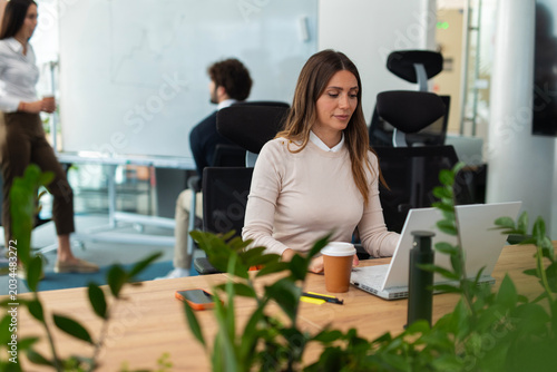 Photos Woman working on laptop in modern office environment