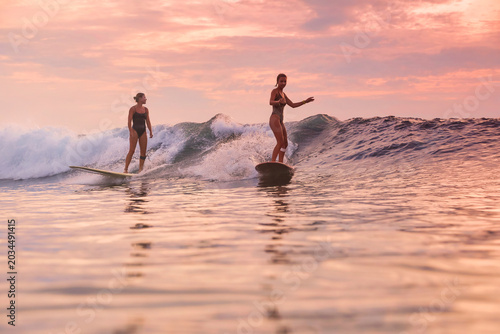 Two Surfers Sharing Sunset Swell, Matching Pace And Friendly Exchange, Mutual Support, Warm Orange Sky,