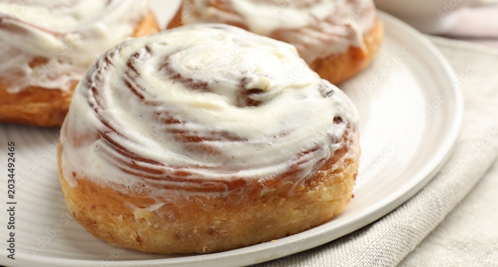 Fototapeta premium Tasty cinnamon rolls with cream on table, closeup