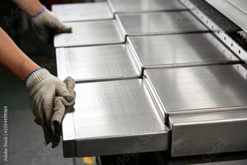 Foto Worker's hands in protective gloves carefully handling polished metal sheets on