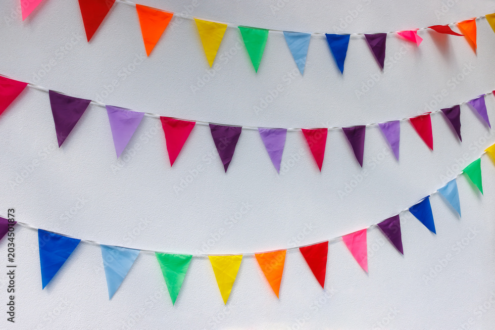 Fototapeta premium Colorful bunting flags on white wall for party celebration. Background with copy space