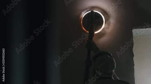 Worker polishing interior wall with illuminated drywall sanding machine