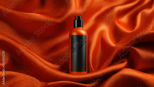 An orange product bottle with a black label and cap is elegantly displayed on a rich, textured orange fabric, highlighting its design.