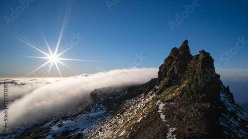 Rocky mountain peak above clouds in Iceland.