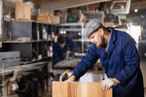 Bild auf Leinwand Experienced furniture assembler assembles wooden table at furniture factory