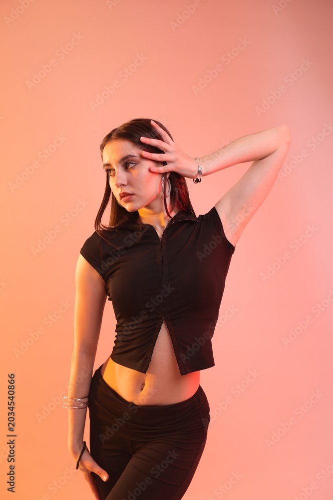 Fototapeta premium Young hip-hop dancer in stylish clothes posing on color background