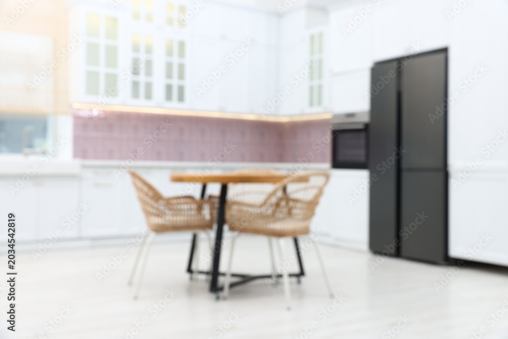 Fototapeta premium Blurred view of stylish kitchen interior with wooden table and chairs
