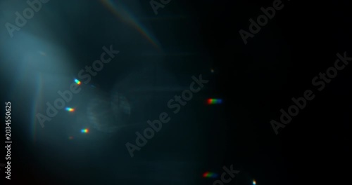 Super slow motion blue lens flare moving across black background. Cinematic optical overlay with rainbow reflections and glowing streaks for VFX compositing effects.