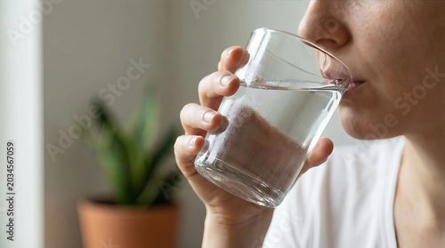 Close-up of person drinking clean water from glass, hydration and wellness concept