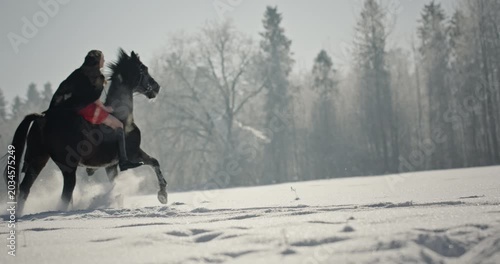 Woman riding a black horse in a snowy winter landscape