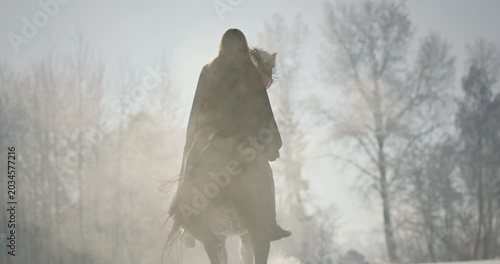 Woman riding a powerful rearing horse in winter