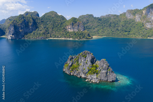 Surrounded by coral, rugged limestone islands rise from Bacuit Bay, El Nido. This area in the Philippines is a popular vacation destination due to its coral reefs, beaches, and limestone islands.