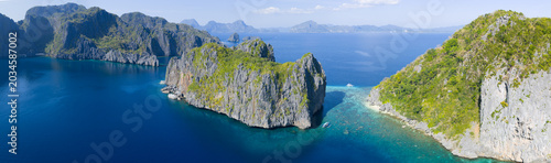 Surrounded by coral, rugged limestone islands rise from Bacuit Bay, El Nido. This area in the Philippines is a popular vacation destination due to its coral reefs, beaches, and limestone islands.