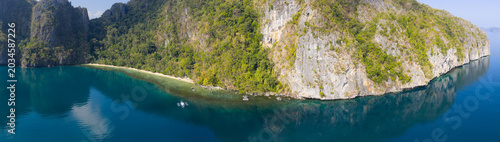 Calm water bathes a dramatic limestone island in Bacuit Bay, El Nido. This scenic area in the Philippines is a popular vacation destination due to its coral reefs, beaches, and hidden lagoons.