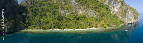 Calm water bathes a dramatic limestone island in Bacuit Bay, El Nido. This scenic area in the Philippines is a popular vacation destination due to its coral reefs, beaches, and hidden lagoons.