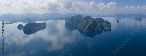 Calm water surrounds majestic limestone islands in El Nido, Philippines. This scenic area of Palawan is a popular vacation destination due to its reefs, beaches, and rock islands.