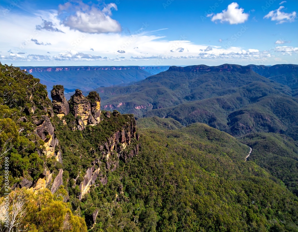 Obraz premium Dramatic Sandstone Cliffs Overlooking Vast Forested Mountain Valley Under Bright Blue Sky