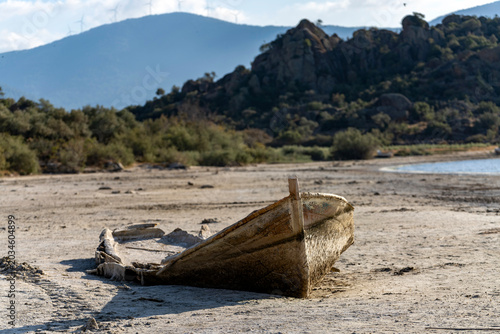 Принти на полотні Abandoned decayed wooden fishing boat on dried cracked lake shore mud crust due