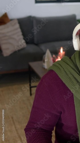 Vertical video: Reacting to camera pull, host in olive-scarf recording into mic at home, copy space