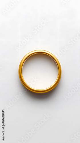 A simple, elegant gold ring sits centered on a clean white background, showcasing its lustrous shine and timeless design