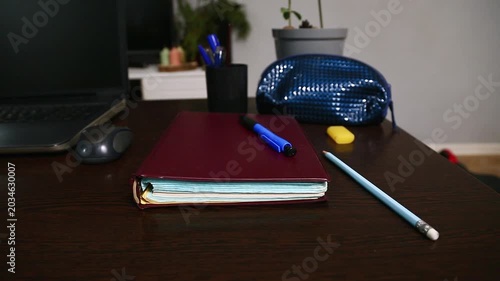 Office work desk with a wood table. Computer, notebook with blue pen, pencil and flower in pot in the study home room. Education, learning concept in different angles. Closeup