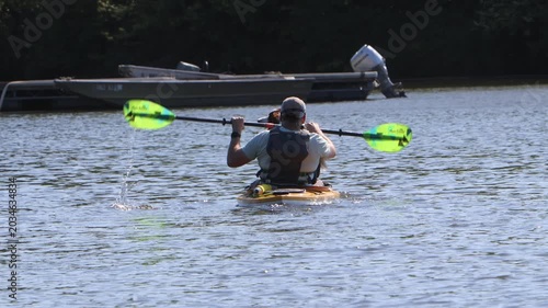 A man and his dog on a kayaking paddling through lake water.