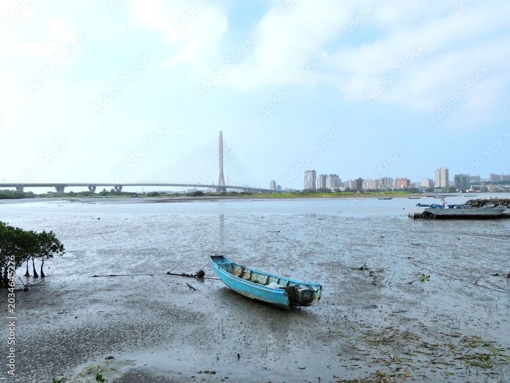 Fototapeta premium Blue Boat on Mudflat Below Tamkang Bridge