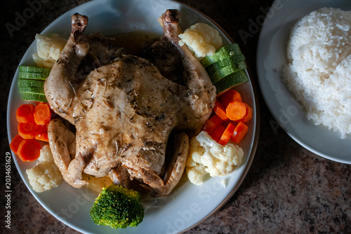 Fotografie Pollo al horno a las yerbas con mantequilla servido en un plato blanco con veget