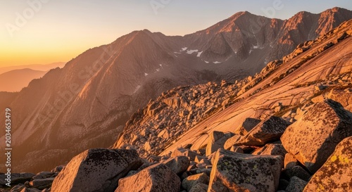 Boulder-strewn mountain slopes bathed in golden sunrise light