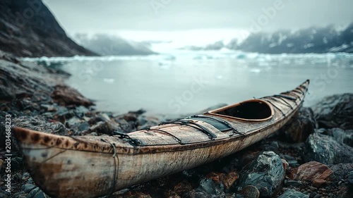 Traditional kayak resting on rocky shore with icebergs