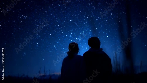 Two silhouettes gazing at a starry night sky