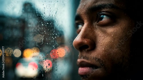 Thoughtful man gazes out at a rainy city scene