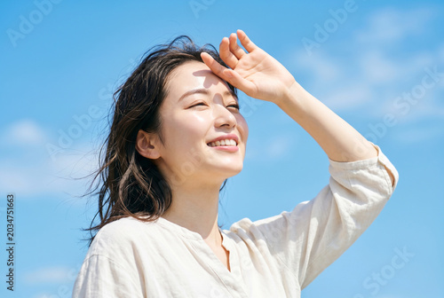 Plakat 夏の青空と眩しい日差しを見上げる日本人女性