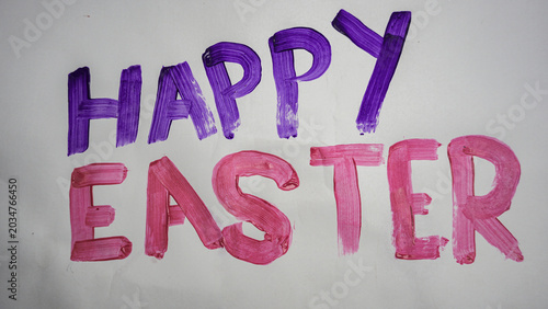 The words 'HAPPY EASTER' are painted in cheerful purple and pink on a white background, adorned with decorative Easter eggs to signify the holiday.