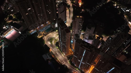 Aerial tracking shot of illuminated high-rise buildings in Hong Kong at night.