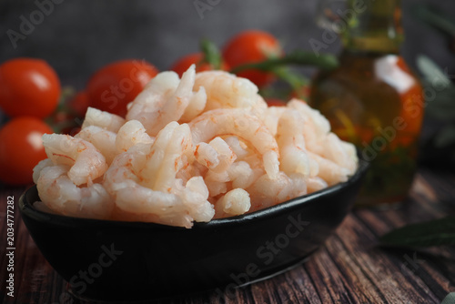 Foto Fresh shrimp on a black plate with tomatoes and oil
