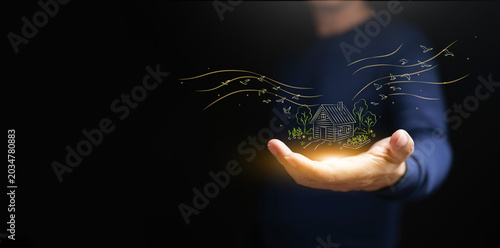 Photos A man holding glowing rural home drawing with trees and birds on dark copy space