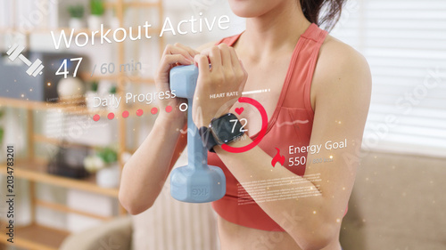 Asian women exercising at home with kettlebell fitness tracking digital overlay display heart rate energy goal workout progress health wellness technology
