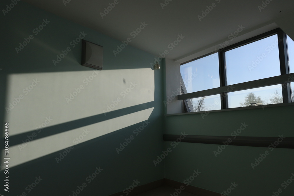 Fototapeta premium Sunlight slices across pale blue walls