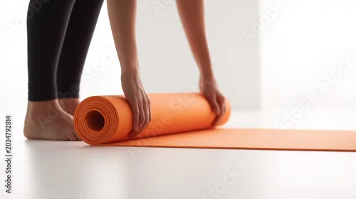 Fototapeta na wymiar Minimal bright yoga scene with a woman rolling out an orange yoga mat