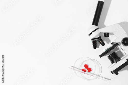 Modern microscope with blood samples and petri dish on white background