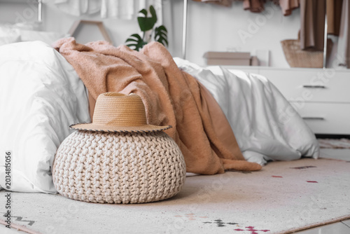 Valokuva Interior of light bedroom with cozy bed, stylish wardrobe and hat on pouf, close