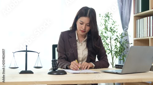 Female lawyer attending an online meeting at her office desk, working with legal documents and a laptop, representing legal consultation, justice, and professional services.