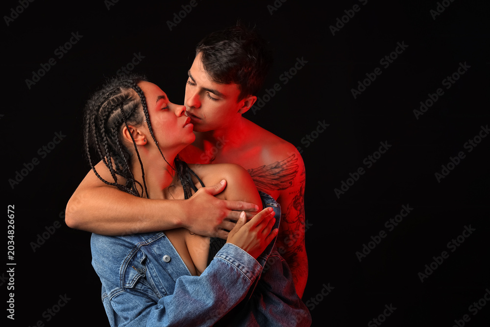 Fototapeta premium Young couple kissing on black background